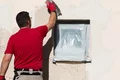 Heimwerker trägt Putz auf Fassade um Fenster auf, selbstgemachte Renovierung mit Baumit-Produkten, Schritt-für-Schritt-Anleitung.