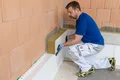 Heimwerker dämmt Fassade mit Mineralwolle; Schritt in der Anleitung zur Außendämmung auf Baumit-Website.