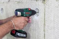 Mann montiert Dämmstoff mit Akkubohrschrauber an Wand für energiesparende Sanierung.