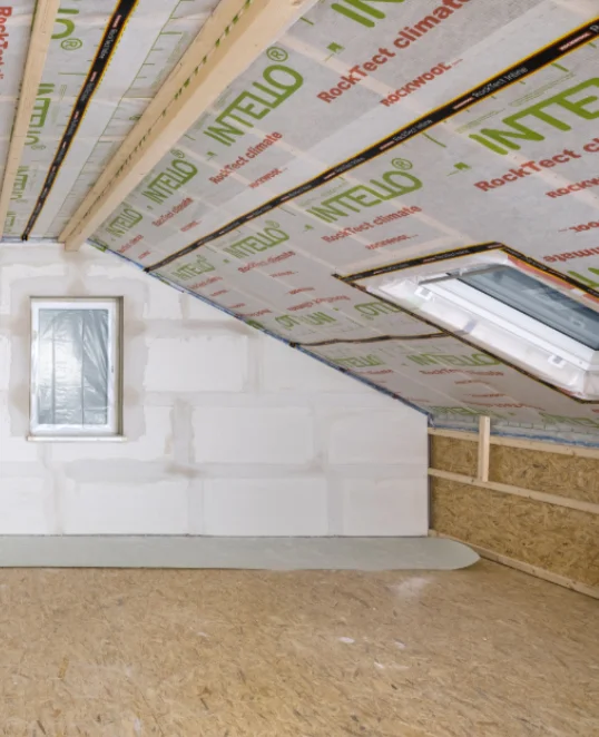 Dachgeschoss-Renovierung mit Dämmung und Trockenbau; isolierte Dachschräge mit Oberlicht, fertige Innenverkleidung.