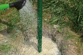 Mit einer Giesskanne wird Wasser auf den Garten- und Landschaftsbaubeton Fix geschüttet.