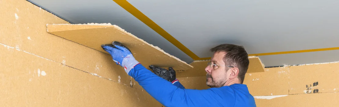 Mann d&auml;mmt Decke mit D&auml;mmplatten; Heimwerkerprojekt mit Schritt-f&uuml;r-Schritt-Anleitung zur effektiven W&auml;rmed&auml;mmung.