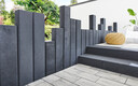 Terrasse moderne avec dalles en pierre grise claire et palissades anthracite.