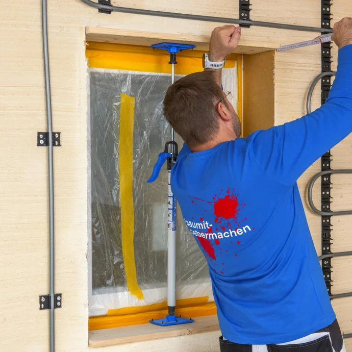 Heimwerker misst Fensteröffnung für Renovierung mit Baumit-Produkten aus.
