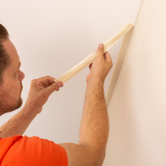 Malerkrepp als Abschluss der gestrichenen Wand nach dem Streichen mit Wandfarbe entfernen