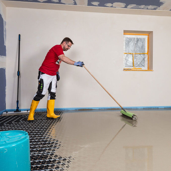 Mann entlüftet die frisch eingebaute Nivelliermasse mit einer Stachelwalze.