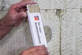 Heimwerker misst Dämmplatte mit einem Zollstock zur Renovierung oder Dämmung von Wänden.