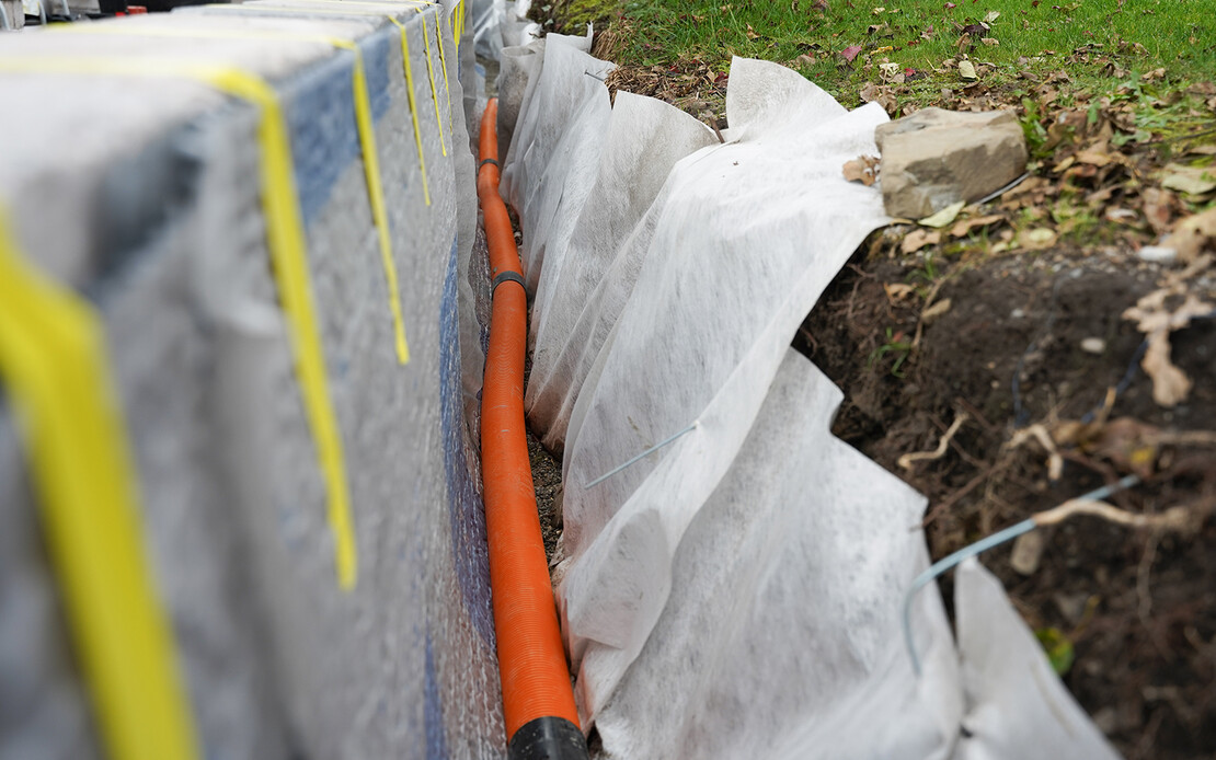 Drainagerohr auf dem Filterkies an der Gartenmauer verlegen.