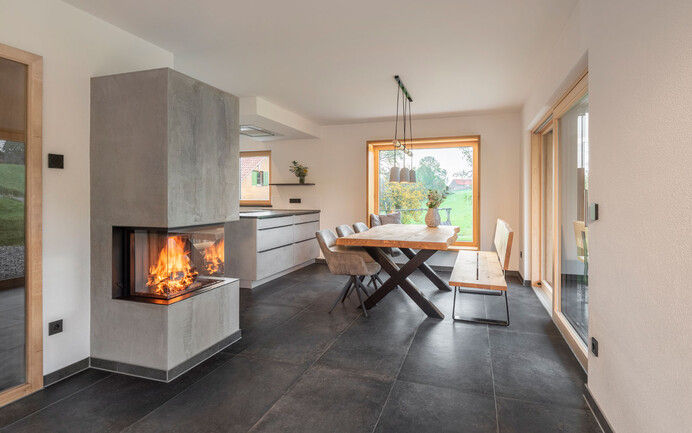 Wohnzimmer in modernem Design mit Kamin in Betonoptik, Granitboden und moderner Einrichtung mit wohngesundem, feinem, brillantweissem Strukturputz InStyle Edelweiss.