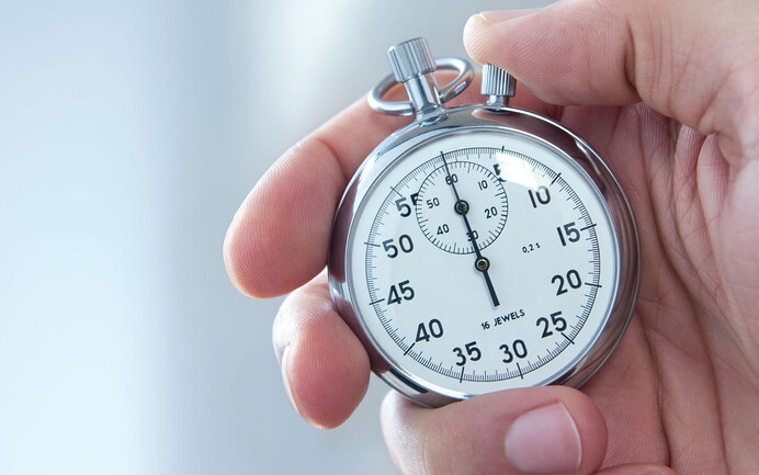 Nahaufnahme: Person hält eine Stoppuhr in der Hand mit unscharfem Hintergrund.