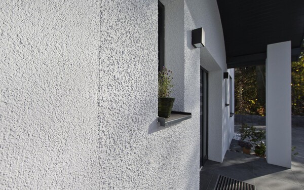 Einfamilienhaus in Weiss. Die Fassade ist mit verschiedenen Putzstrukturen mit feiner und grober Körnung gestaltet.