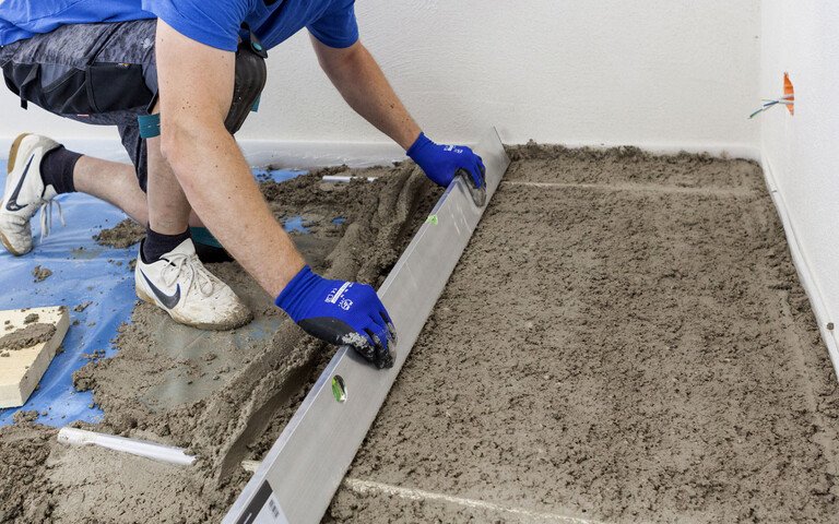 Der frische Mörtel wird auf den beiden Abziehlehren mit einer Abziehlatte abgezogen.