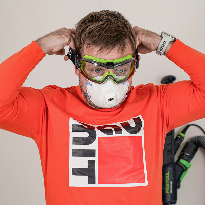 Der Heimwerker schütz sich beim Schleifen mit einer Atemschutzmaske und geschlossenen Schutzbrille.
