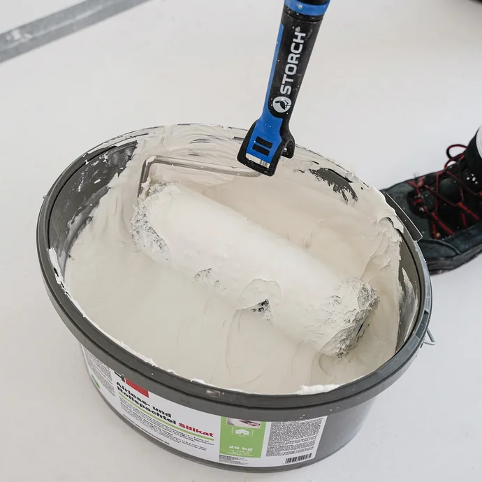 Seau de peinture murale blanche, avec un rouleau &agrave; peinture &agrave; c&ocirc;t&eacute; ; adapt&eacute; aux projets de bricolage et aux r&eacute;novations murales simples.