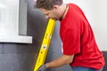 Heimwerker richtet Dämmplatten mit gelber Wasserwaage an der Wand aus.