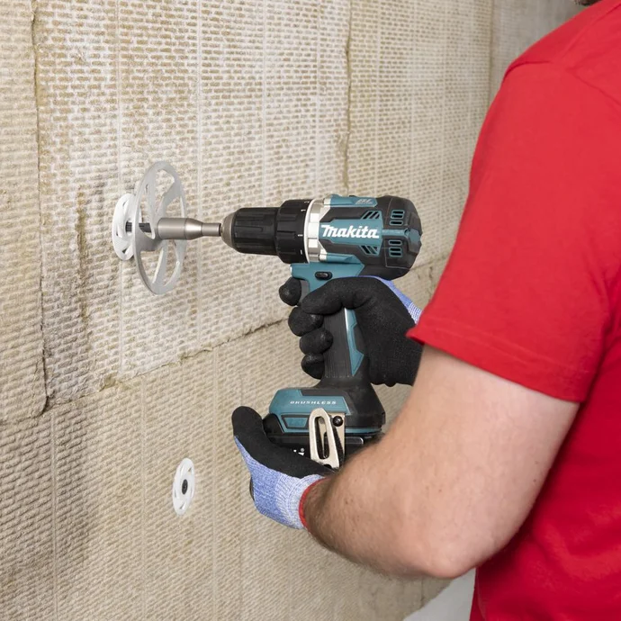 Une personne fixe des panneaux isolants au mur à l'aide d'un outil électrique dans le cadre d'un projet de bricolage.