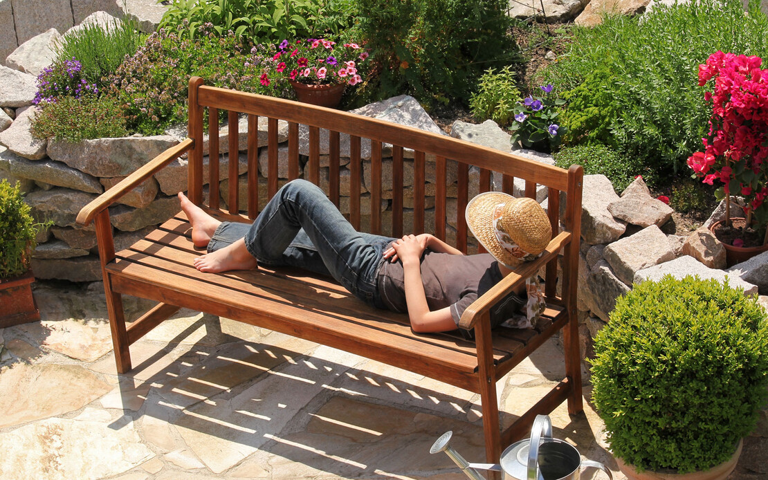 Ein Frau entspannt in ihrem bl&uuml;henden Garten.