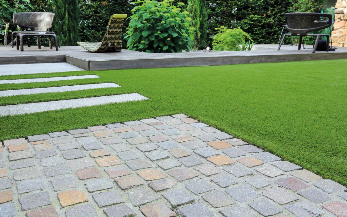 Gepflegter Garten mit Steinweg und Kunstrasen, ideal f&uuml;r DIY-Projekte zur Versch&ouml;nerung des Au&szlig;enbereichs.