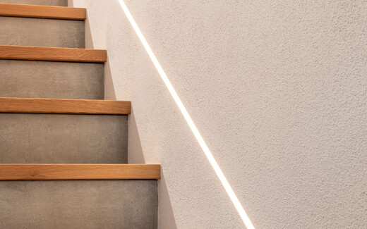 Moderner Treppenaufgang mit Beton und Holz mit indirekter Beleuchtung und brillantweissem feinen InStyle Edelweiss.