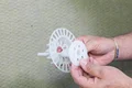 Une personne tient une cheville en plastique avec une rondelle isolante, idéale pour la fixation de panneaux isolants sur les façades de maisons.