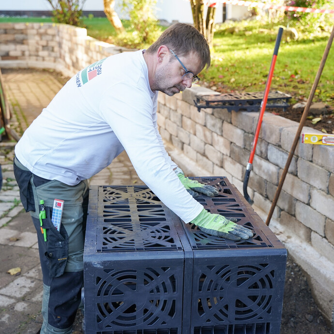 Heimwerker setzt die Seitenwände der Sickerbox so ein, bis sie fest eingerastet sind.