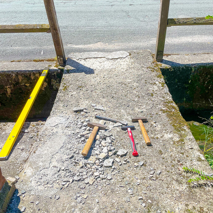 Lose und brüchige Teile sind auf dem Betonboden abgeschlagen. Hammer, Wasserwaage und weitere Werkzeuge werden dafür benötigt.