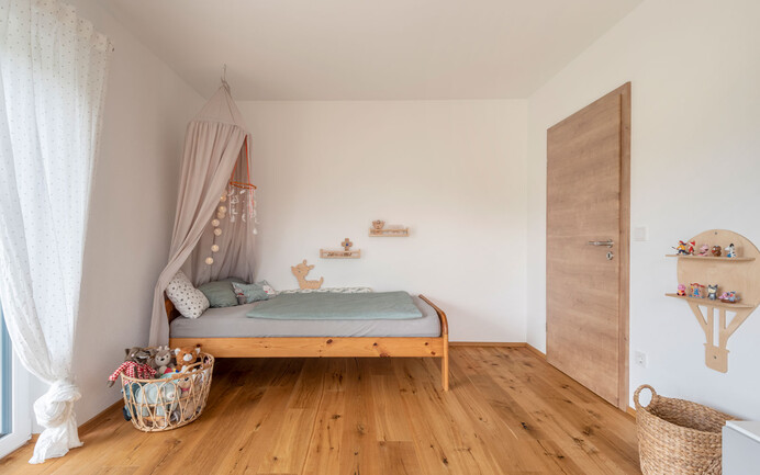 Modernes Kinderzimmer mit Bett und Spielzeug, Holzboden und dem brillantweissen Edelputz InStyle Edelweiss mit gefilzter Putzstruktur für ein angenehmes Raumklima.