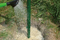 Mit einer Gießkanne wird Wasser auf den Garten- und Landschaftsbaubeton Fix geleert.