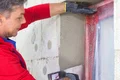 Heimwerker verputzt Wand um Fenster mit Armierungsgewebe für bessere Dämmung.