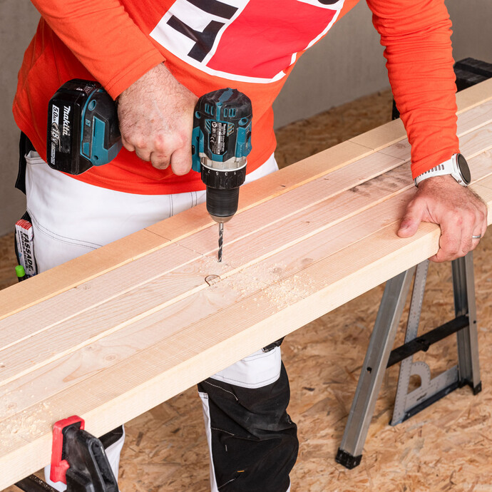 Heimwerker bohrt Löcher im Kantholz vor.