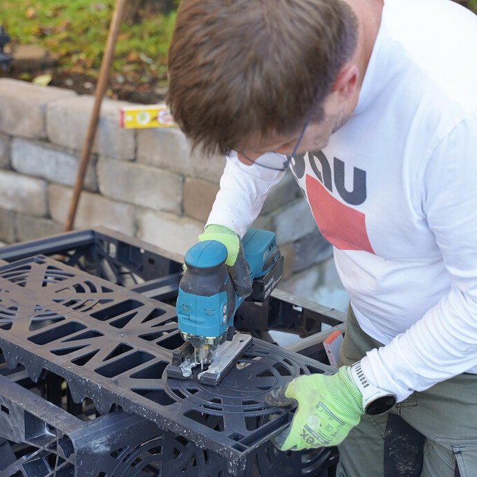 Mit einer Stichsäge wird die Rohrdurchführung an der Seitenwand der Sickerbox ausgesägt.