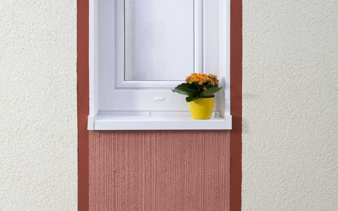 Fenster mit Blumentopf auf dem weißen Fensterbrett. Es sind zwei rote Streifen links und rechts die unterhalb des Fensters mit hellroter Farbe ausgefüllt sind.