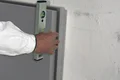Hand richtet Dämmplatte auf Wand mit Wasserwaage aus.