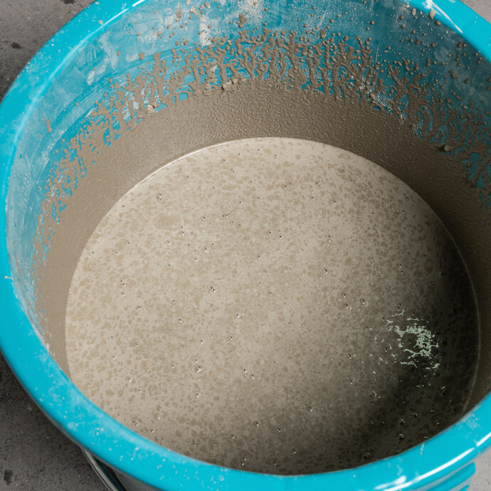 Nahaufnahme Foto: Blauer Eimer mit angerührter Ausgleichsmasse - Reifezeit beachten: Die Ausgleichsmasse bleibt ein paar Minuten stehen bis sie erneut durchgemischt wird.