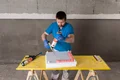 Un bricoleur applique du mastic sur un panneau isolant dans un bâtiment en gros œuvre.