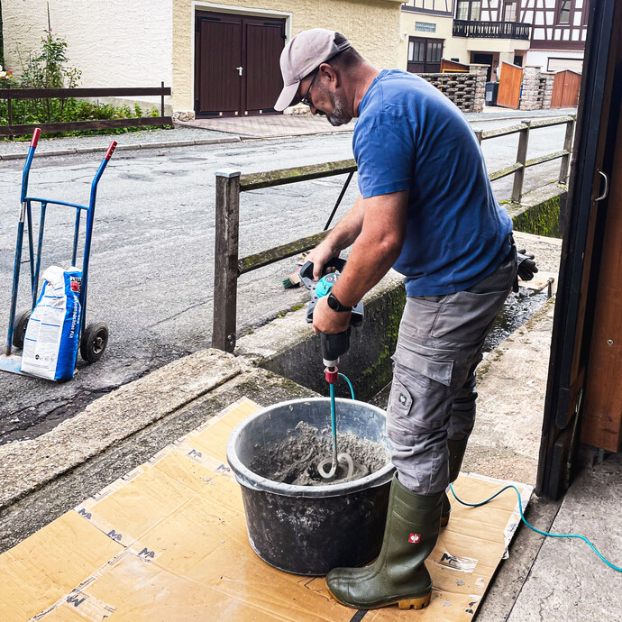 Der Baumit Gefällemörtel wird im Mörtelkübel mit einem elektrischen Rührwerk angerührt.