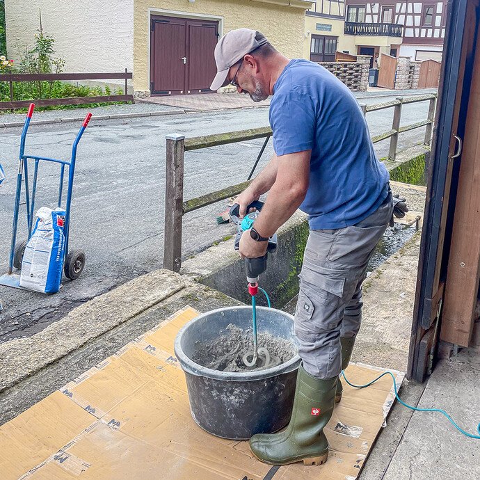 Der Baumit Gefällemörtel wird im Mörtelkübel mit einem elektrischen Rührwerk angerührt.