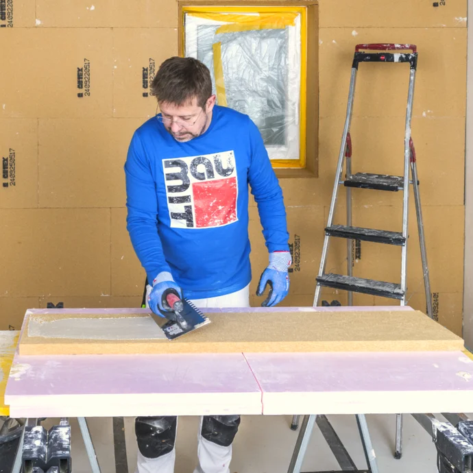 Heimwerker glättet Putz auf Dämmsystem; Schritt-für-Schritt-Anleitung auf baumit-selbermachen.de für DIY-Projekte.