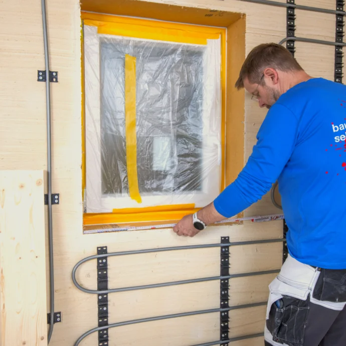 Heimwerker beim Anbringen von Dämmplatten an einer Aussenwand, um Energieeffizienz zu verbessern.