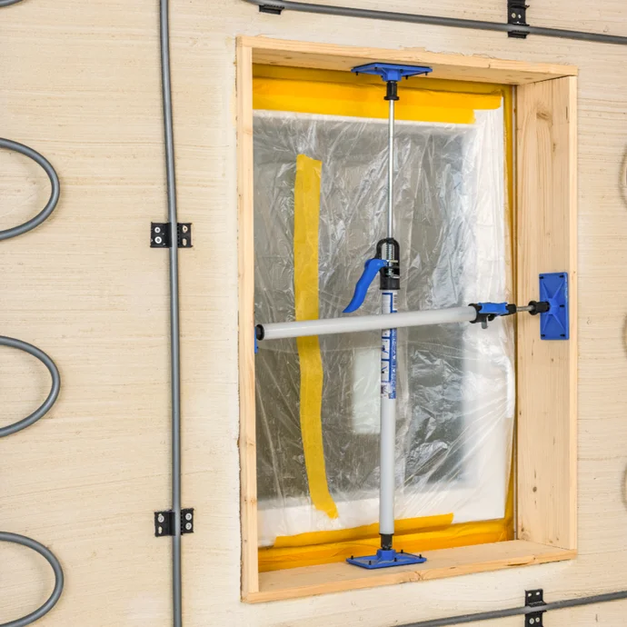 Temporäre Fensterabdeckung mit Schutzfolie und Spannstange zur Vorbereitung von Renovierungsarbeiten.
