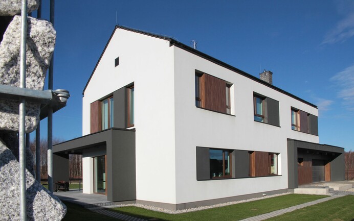 Maison individuelle avec façade en crépi combinée avec du bois et des surfaces anthracite