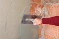 Auftragen von Putz auf Ziegelmauer mit Kelle, Schritt-für-Schritt-Anleitung für Heimwerker.