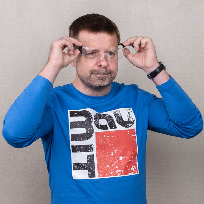 Person zieht zum Schutz eine Sicherheitsbrille auf. So ist der Heimwerker beim Löcher bohren im Ziegelmauerwerk geschützt.