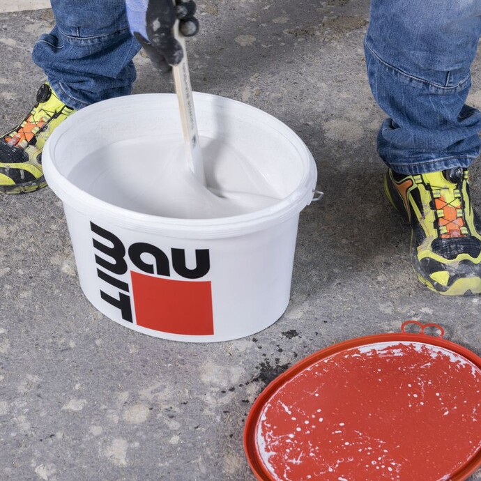 Grundierung im Baumit-Eimer wird mit einem Rührstab verrührt.