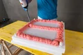 Une personne remplit un cadre de mousse de montage sur un support en polystyrène.
