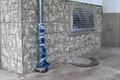 Mur de gros œuvre avec fenêtre préparée et tuyau de descente protégé pour l’aménagement de la façade. Idéal pour des conseils de rénovation sur Baumit.