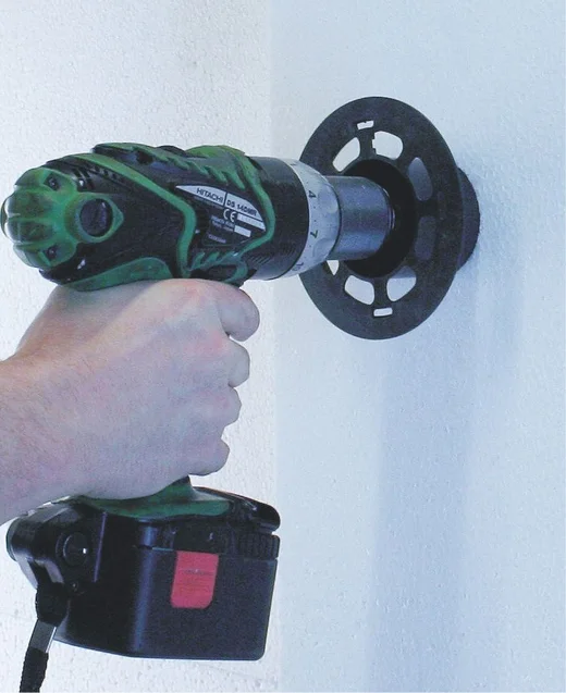 Un bricoleur perce un trou dans le mur à l'aide d'une perceuse sans fil dans le cadre d'un projet de construction ou de travaux de rénovation.