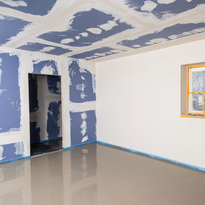 Pièce avec masse d'égalisation fraîchement posée.  Cloisons sèches avec plaques de plâtre et mur crépi avec fenêtre masquée.