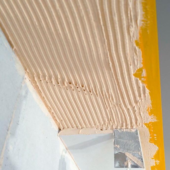 Mit einer Kelle wird Putz auf die Stosskante des Anschlusskeils aufgetragen.