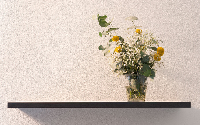 Wände gestalten mit dem wohngesundem Edelputz InStyle Edelweiss in feiner, gefilzter Struktur dekoriert mit Regalbrett und Blumenstrauss.